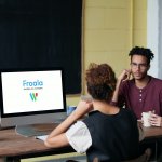 A group of professionals discussing around a computer with Froala's logo on the screen.