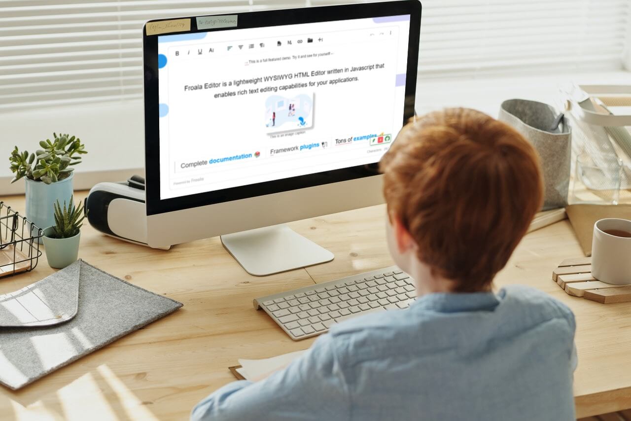 A person working on a computer with the Froala WYSIWYG HTML editor on the screen.